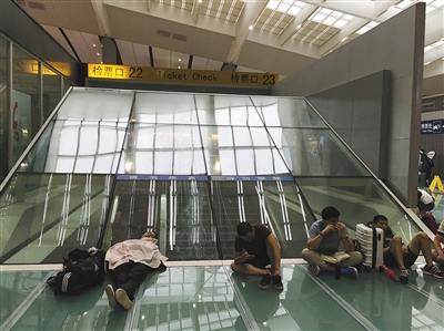 7月下旬,北京南站,旅客在候车大厅席地而坐。